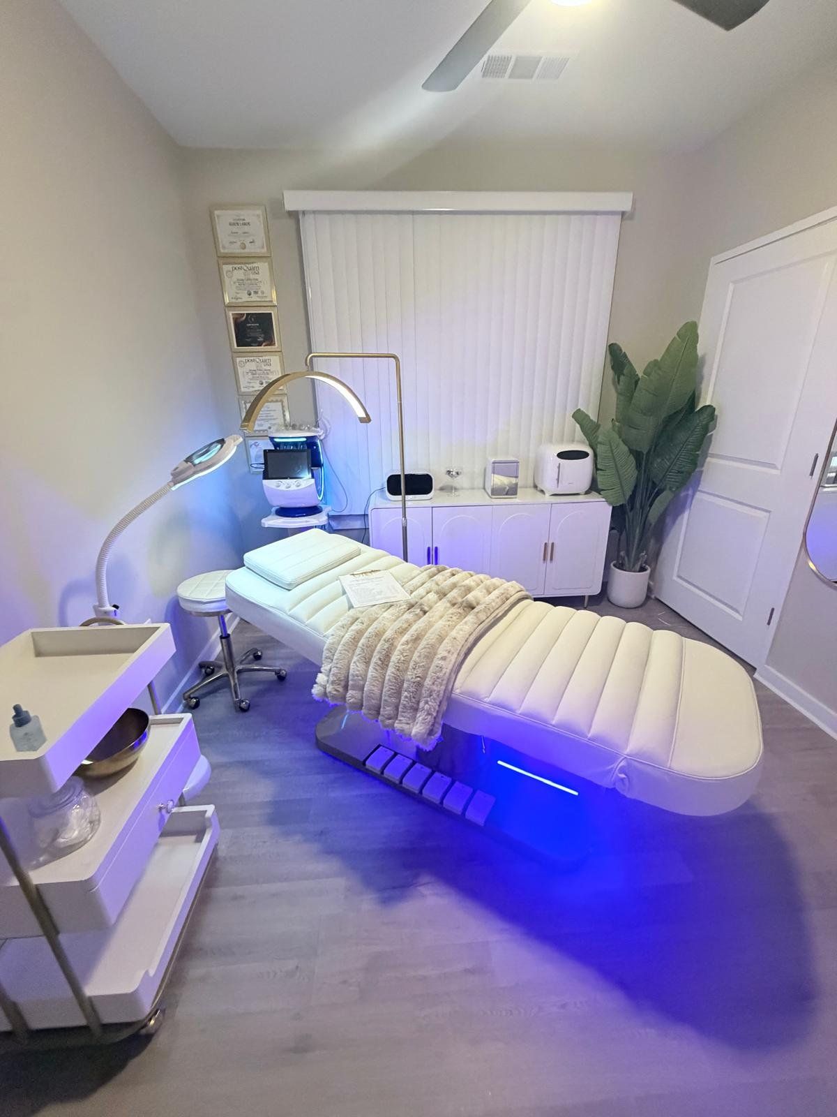 Cabina de GIO Beauty Skin con camilla blanca, lámpara de aro y diplomas en la pared